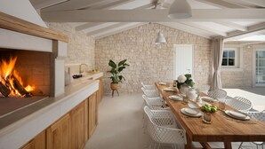 A modern kitchen with a stone wall, wooden cabinets, and a built-in fireplace. - Villa Gabriel Residence (Zminj)