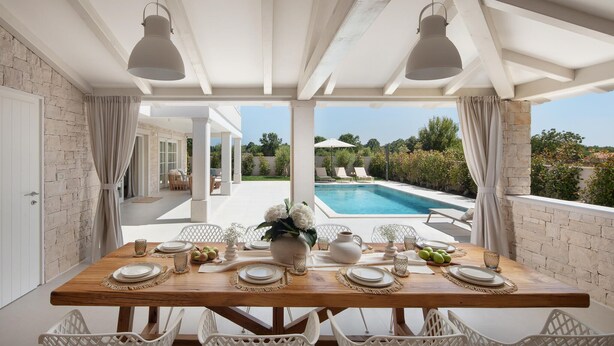 A dining area with a view of a swimming pool and greenery. - Villa Gabriel Residence (Zminj)