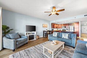 A living room with a TV, two sofas, a coffee table, and a ceiling fan. - Laketown Wharf 320 |Spacious 3BR with Lakefront Balcony & New Flooring | 5 Pools, 2 Hot Tubs, Gym, Beach Access (Panama City Beach)