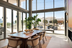 Un comedor moderno con una mesa grande y sillas, ventanas amplias y vistas al exterior.