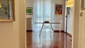 A dining area with a wooden floor, clear chairs, a glass table, and a white radiator. - Bnbook La Residenza di Mondrian (rho)