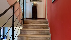 A staircase with a metal railing, a decorative spherical object on a pedestal, and a framed artwork on the wall. - Bnbook La Residenza di Mondrian (rho)