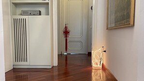 A hallway with a white cabinet, a red decorative item, and a lit glass object on the floor. - Bnbook La Residenza di Mondrian (rho)