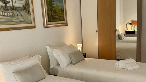A hotel room with two beds, a wooden door, and artwork on the walls. - Bnbook La Residenza di Mondrian (rho)