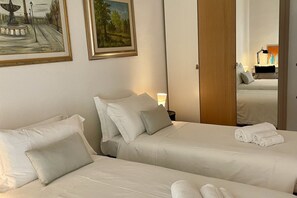 Una habitación de hotel con dos camas, una puerta de madera y obras de arte en las paredes.