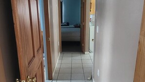 A hallway with wooden doors, tiled flooring, and a ceiling light fixture. - Snowmobiling & Fourwheelering right out on the main trail (Stewartstown)