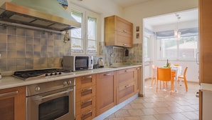 Una cocina moderna con electrodomésticos de acero inoxidable, armarios de madera y un comedor con sillas naranjas.