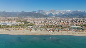 Un paisaje costero con playa, edificios residenciales y montañas al fondo.