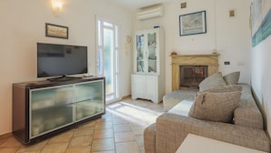 Una sala de estar con televisor de pantalla plana, un mueble, un sofá y una chimenea.
