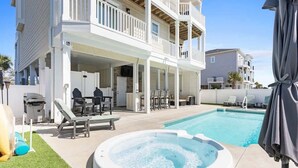 Ein zweistöckiges Gebäude mit überdachter Terrasse, Schwimmbad und Whirlpool.