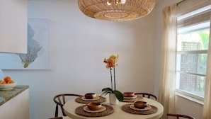 Una mesa redonda de comedor con seis sillas, un centro decorativo tejido y un florero con flores.