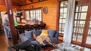 A cozy living room with a grey sofa, a glass coffee table, and a wooden ceiling. - Secluded rustic cottage charm, opposite river walk, close to town. Pet friendly! (Bridgetown)