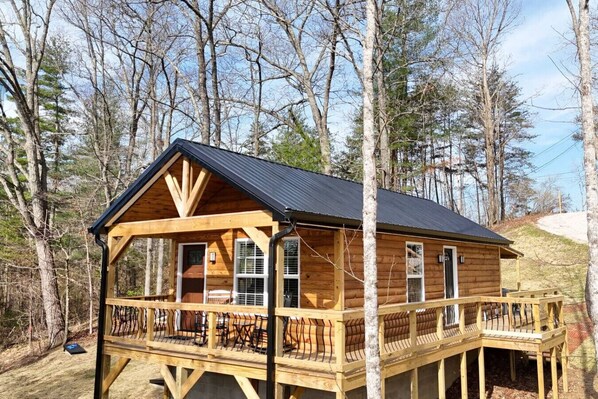 A wooden cabin with a balcony, surrounded by trees. - Alone At Last- Hot tub, Fireplace, Fire pit (Campton)