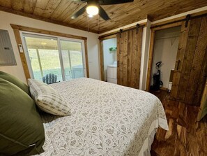 A bedroom with a bed, a ceiling fan, and wooden walls. - Alone At Last- Hot tub, Fireplace, Fire pit (Campton)