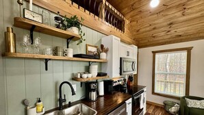 A kitchen with wooden shelves, a sink, and a window. - Alone At Last- Hot tub, Fireplace, Fire pit (Campton)