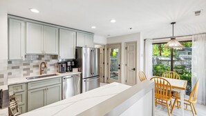 A modern kitchen with stainless steel appliances, a white countertop, and light grey cabinets. - Single Level Home with Game Room and Putting Greens (Hilton Head Island)