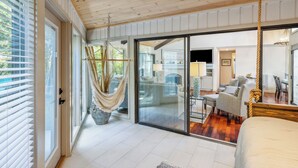 A spacious room with a large bed, a hammock, and a sliding glass door leading to a dining area. - Single Level Home with Game Room and Putting Greens (Hilton Head Island)