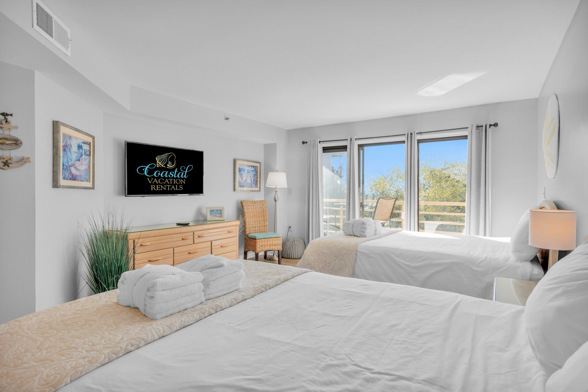 Une chambre avec deux lits, une télévision et un balcon offrant une vue.