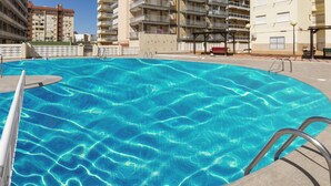 Une piscine à l’eau d’un bleu cristallin, entourée d’un espace aménagé avec une échelle en métal et un banc.