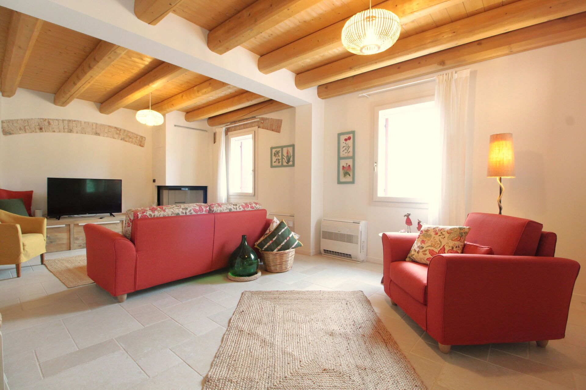 A living room with a red sofa, a television, a lamp, and a fireplace.