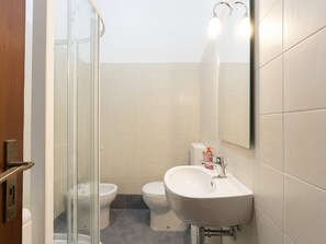 Une salle de bain moderne avec une douche à parois de verre, un lavabo blanc et des toilettes.
