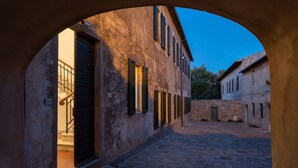 A narrow cobblestone street with buildings on either side, featuring arched doorways and windows. - Sunset Populonia by Geco Vacation Rentals (Populonia)