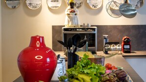 A kitchen counter with a red gas canister, a salt shaker, and fresh vegetables. - Sunset Populonia by Geco Vacation Rentals (Populonia)