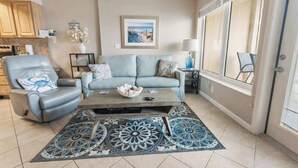 A living room with a sofa, armchair, coffee table, and decorative rug. - Boardwalk 584 (Gulf Shores)