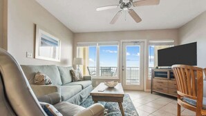 A living room with a sofa, coffee table, and TV. There is a balcony with a view. - Boardwalk 584 (Gulf Shores)