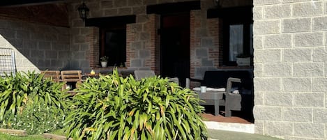 A stone building with a tiled roof, outdoor seating, and a well-maintained garden.