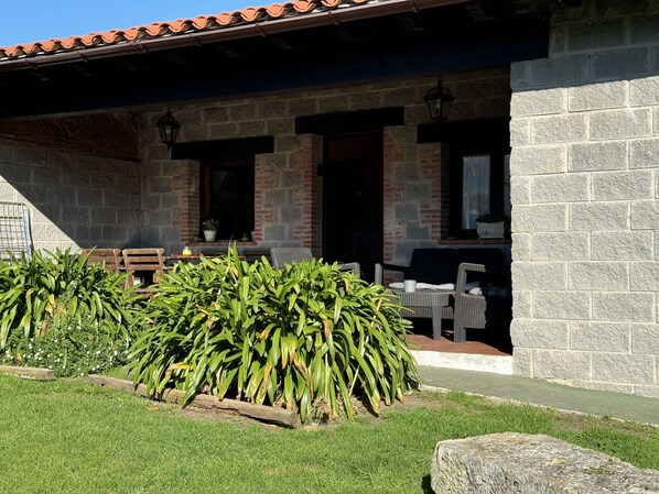 A stone building with a tiled roof, outdoor seating, and a well-maintained garden.