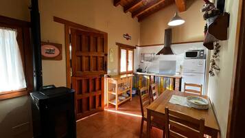 Een koelkast, een magnetron, kookgerei, borden en bestek, eettafels