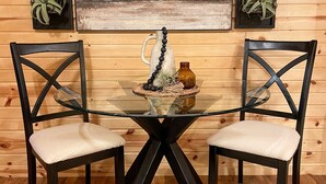 A dining table with two chairs, a glass top, and a wooden floor. - The Dens at Bear Rock 2 with stairs access (Custer)