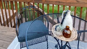 A wooden deck with a table and chairs, overlooking a rural landscape with a red building and a large tree. - The Dens at Bear Rock 2 with stairs access (Custer)