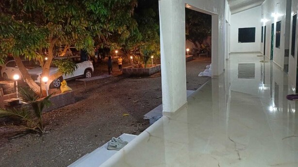 Un espacio al aire libre cubierto con un sendero pavimentado, árboles y coches aparcados.