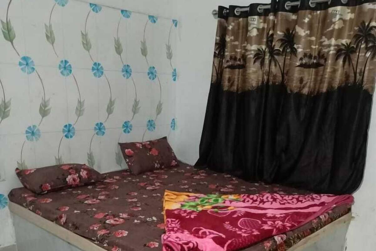 Ein Bett mit floraler Bettdecke, ein Kopfteil mit Blumenmuster und ein Vorhang mit tropischem Druck.