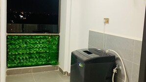 A bathroom with a toilet, a water heater, and a window with a view of a cityscape at night. - Beautiful 1-Bed Apartment in nairobi (nairobi)