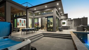 Une maison moderne dotée d’une piscine, d’un espace salon extérieur et d’un jacuzzi.