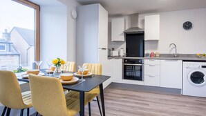 A modern kitchen with a dining area, including a table set for four, chairs, and a view of the outside.