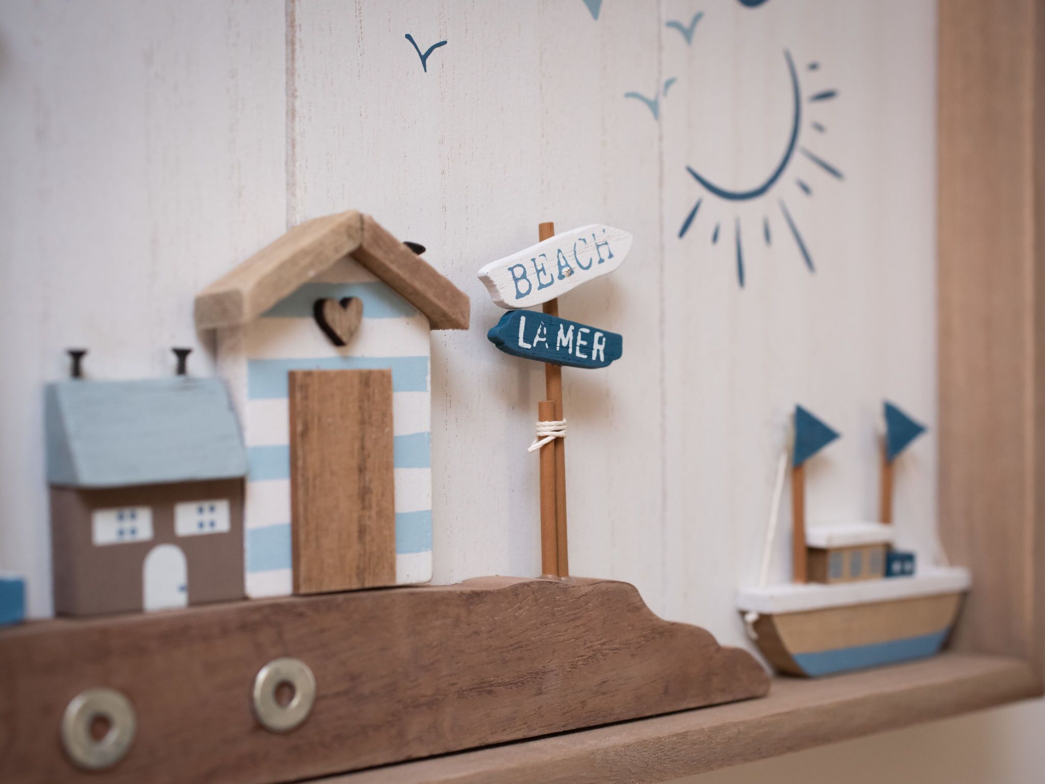 Una maqueta de madera de una casa de playa con un cartel que dice "BEACH" y "LA MER".