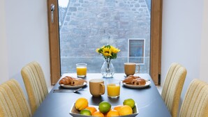 Ein Frühstückstisch mit Croissants, Orangensaft und einer Obstschale.