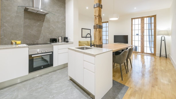 A modern kitchen with a central island, a built-in oven, and a large window.