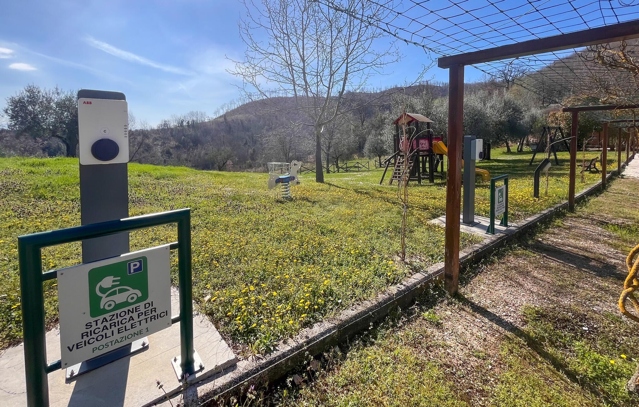 A parking sign for electric vehicles and a charging station in a park.