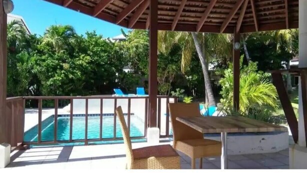 Un'area esterna coperta con piscina, sedie e tavolo.