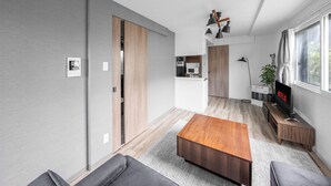 A modern living room with a wooden coffee table, grey sofa, and a TV on a wooden stand. - SERAPHIC 101 (Chitose)