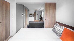 A modern hotel room with a large bed, a wooden wardrobe, a kitchenette, and a view into the living area. - SERAPHIC 101 (Chitose)