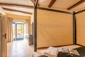Une pièce avec un lit, une fenêtre avec des rideaux, une porte et une vue sur l’extérieur.
