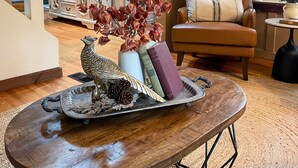 Un accogliente soggiorno con un tavolino in legno, una poltrona marrone e un vassoio decorativo con una scultura di uccello.