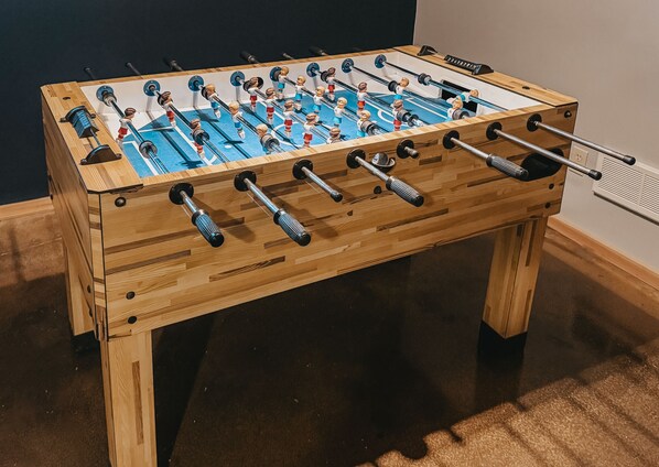 A wooden foosball table with multiple rods and figures.