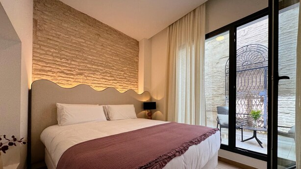 A bedroom with a large bed, a view of the outside, and a textured wall. - Redes Royale Apartments ·B1· by Misterhost (Sevilla)